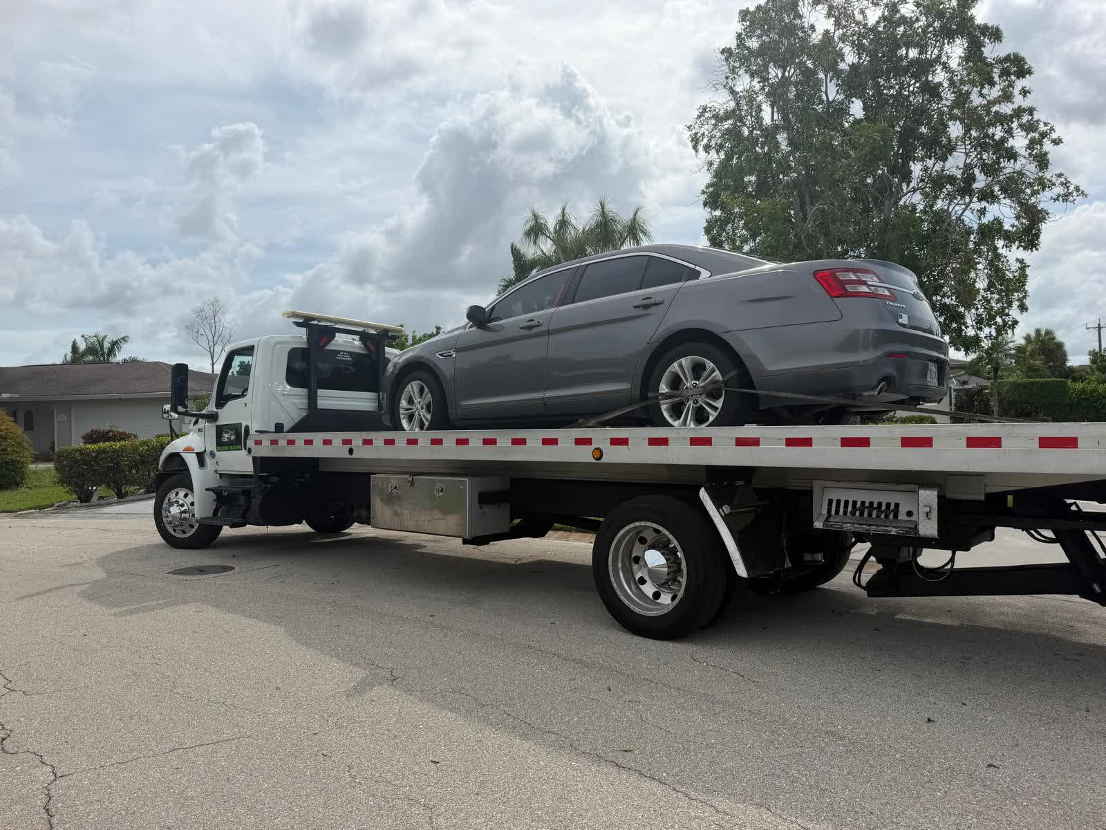 Grúa de Brayan Towing con un sedán cargado en una calle de Cape Coral